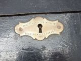 a brass keyhole on a black wooden drawer