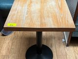 une table en bois avec un piètement en métal noir posée sur un parquet