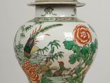 a vase with a lid sitting on a wooden table