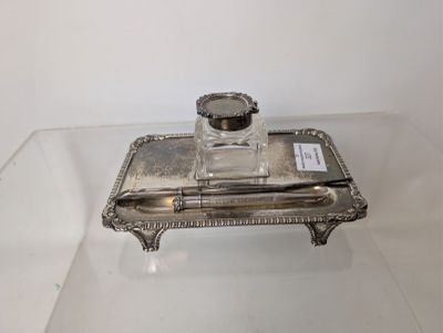 an antique silver plate with a pen and inkwell on it