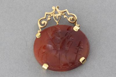 un gros plan d'un pendentif plaqué or orné d'une pierre rouge