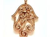 une image d'un pendentif en forme de main de Hamsa sertie d'un diamant, sur fond blanc