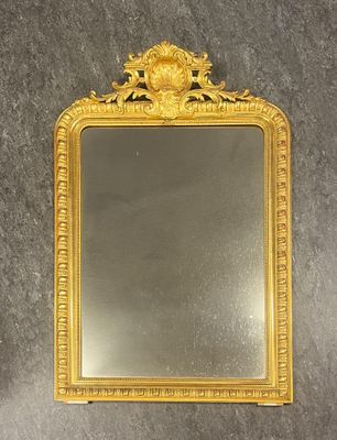 miroir à cadre doré orné d'un motif floral dans sa partie supérieure