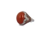 an image of a ring with a red stone surrounded by diamonds