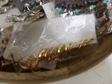 a wooden bowl filled with lots of jewelry on a table