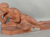 statue d'un homme allongé sur un socle en bois, la main posée sur le menton