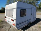 a small white trailer parked in a dirt lot