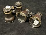 three antique binoculars are sitting on a black cloth