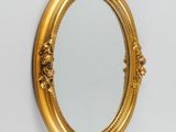 un miroir ovale avec un cadre doré accroché au mur