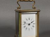 une petite horloge en laiton avec des chiffres romains sur le cadran