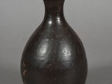 a black vase sitting on a table with a gray background