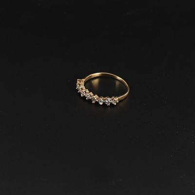 a gold ring with five diamonds on a black surface
