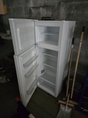 un réfrigérateur blanc dont la porte est ouverte, dans une pièce