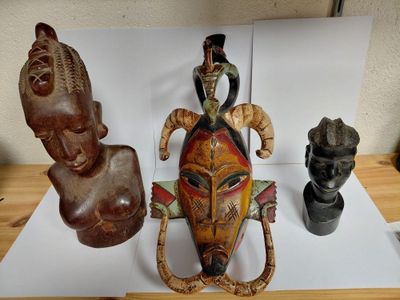 three african masks are sitting on a table next to a vase