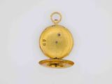 a close up of a gold pocket watch on a white surface