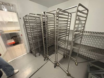 many racks of food in a kitchen with a person walking by