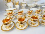 beaucoup d'assiettes et de tasses dorées et blanches sur la table