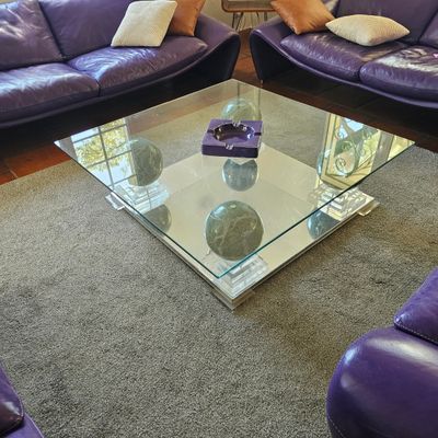 des canapés en cuir violet et une table basse en verre dans un salon