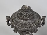an antique silver plate with a lid on a stand