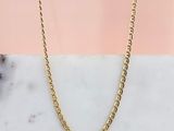 un collier à chaîne en or posé sur une surface en marbre