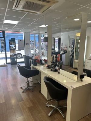 une photo d'un salon de coiffure avec de nombreux fauteuils