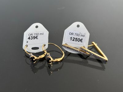two pairs of earrings with tags on them sitting on top of a table