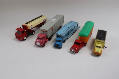 plusieurs camions jouets sont alignés sur une surface blanche