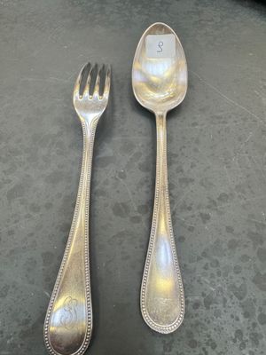two silver spoons and a fork sitting on a table