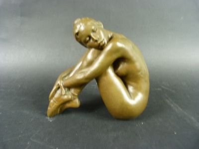 statue en bronze représentant une femme assise à genoux sur une table