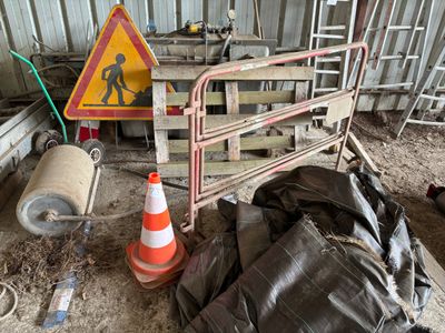 une clôture sur laquelle est accrochée une pancarte de chantier, à côté d'un tas d'ordures