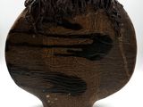 a wooden sculpture of a man ' s head on a white surface