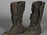 pair of brown boots with green laces on them on a gray surface