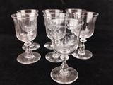 six clear wine glasses sitting on top of a black table