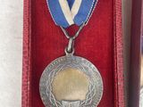 a silver medal in a red box with a ribbon around it
