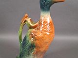 a small ceramic duck with a handle on a gray surface