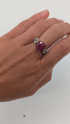 quelqu'un tient une bague sertie d'une pierre rouge