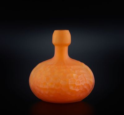 une bouteille en verre orange posée sur une surface noire, avec un fond noir