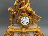 a gold clock with a man sitting on top of it