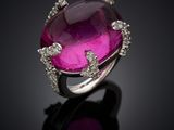 a close up of a pink stone and diamond ring on a black surface