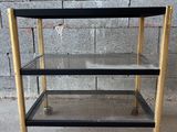 un chariot de bar noir et or avec trois étagères sur roulettes