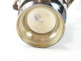 a silver vase with a handle on a white table