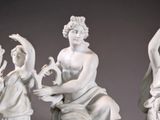 three statues of a man and a woman sitting on a bench