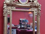 un miroir avec un cadre doré accroché à un mur rose