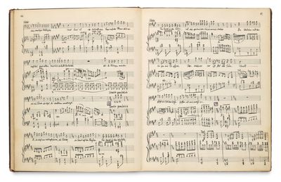 un livre ouvert, orné de notes de musique, posé sur une surface blanche