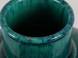 a green vase sitting on top of a white table