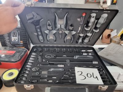 Quelqu'un tient une mallette remplie d'outils posée sur une table.