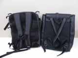 pair of black backpacks sitting on top of each other on a table