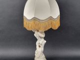 an image of a white lamp with a gold fringe on top of it