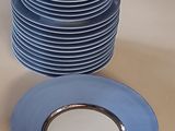 a stack of blue plates on a table with a silver rim