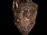 a bronze urn with two cherenshes on top of it